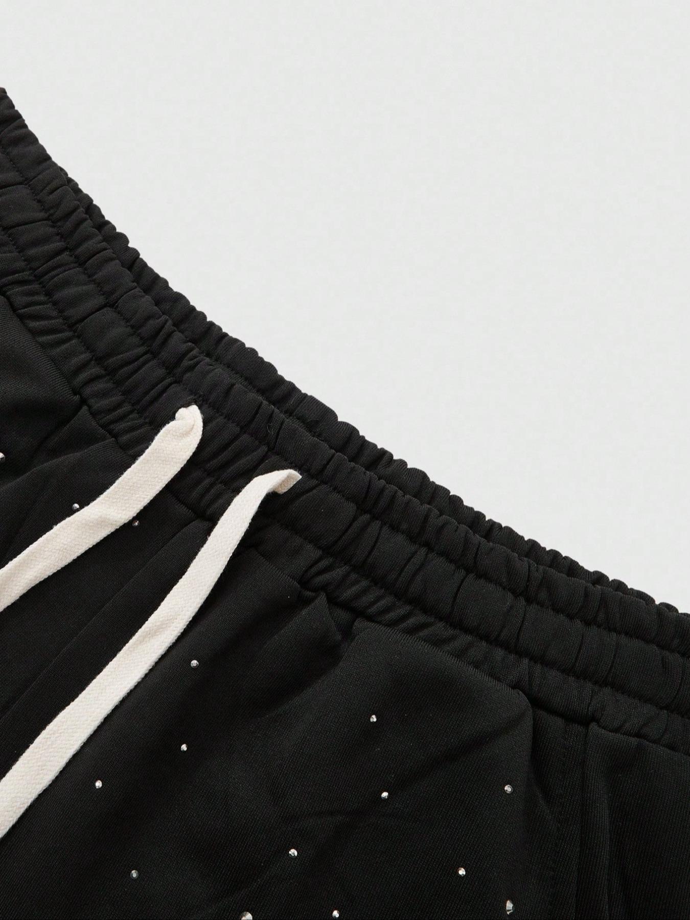 This men's two-piece set features a gothic streetwear design, including a long-sleeved T-shirt with a shimmering flame print and black flared trousers adorned with rhinestones and lettering.