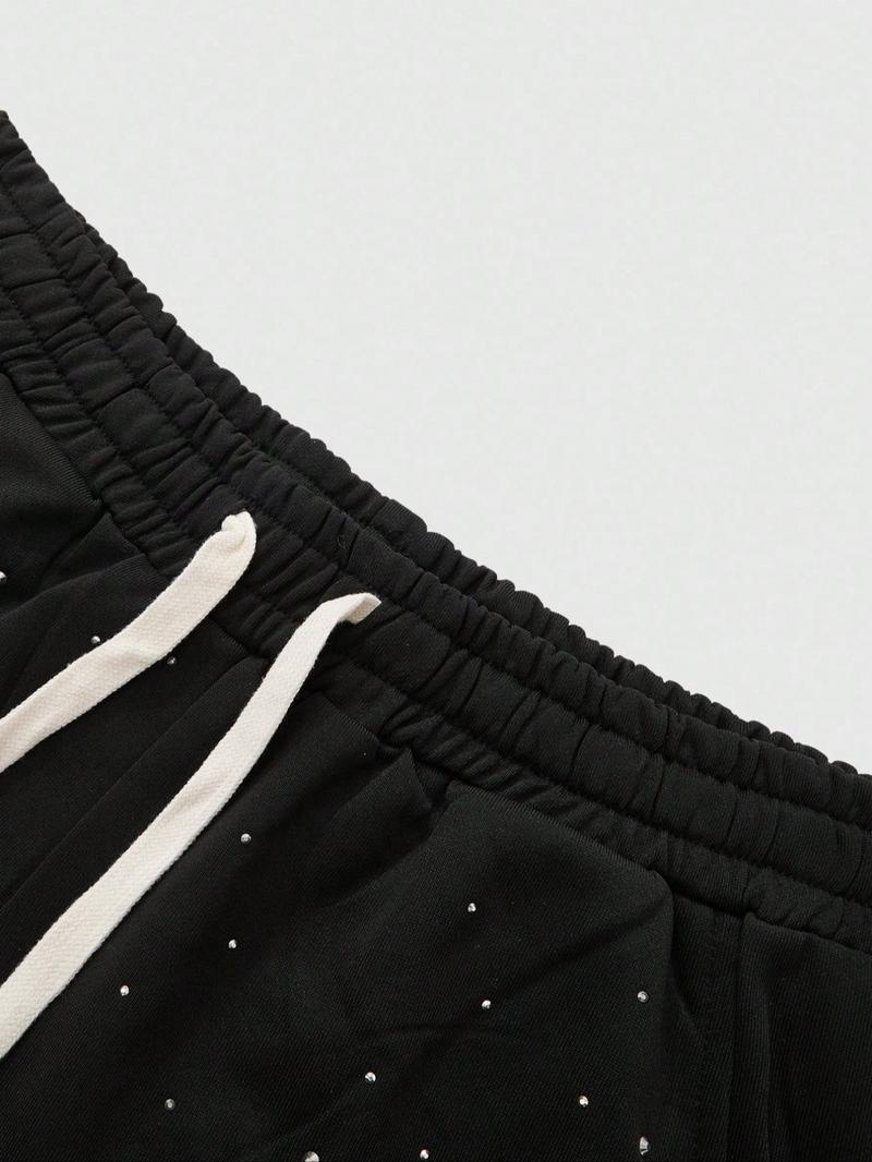 This men's two-piece set features a gothic streetwear design, including a long-sleeved T-shirt with a shimmering flame print and black flared trousers adorned with rhinestones and lettering.