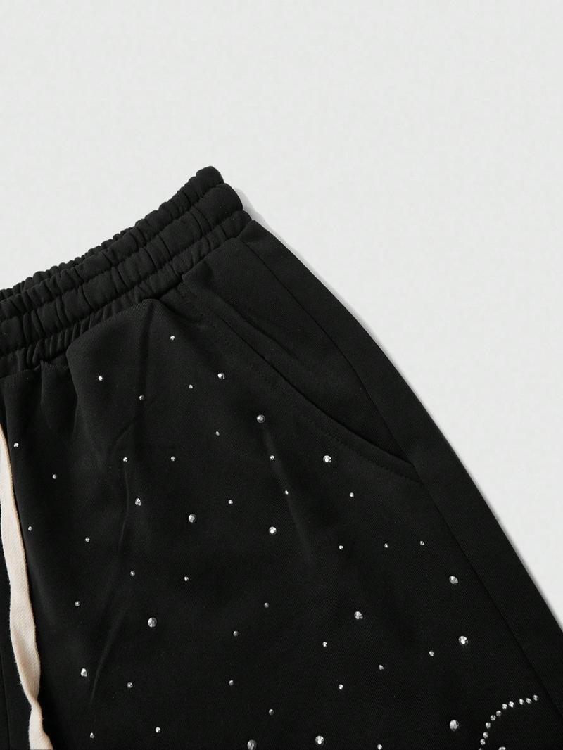 This men's two-piece set features a gothic streetwear design, including a long-sleeved T-shirt with a shimmering flame print and black flared trousers adorned with rhinestones and lettering.