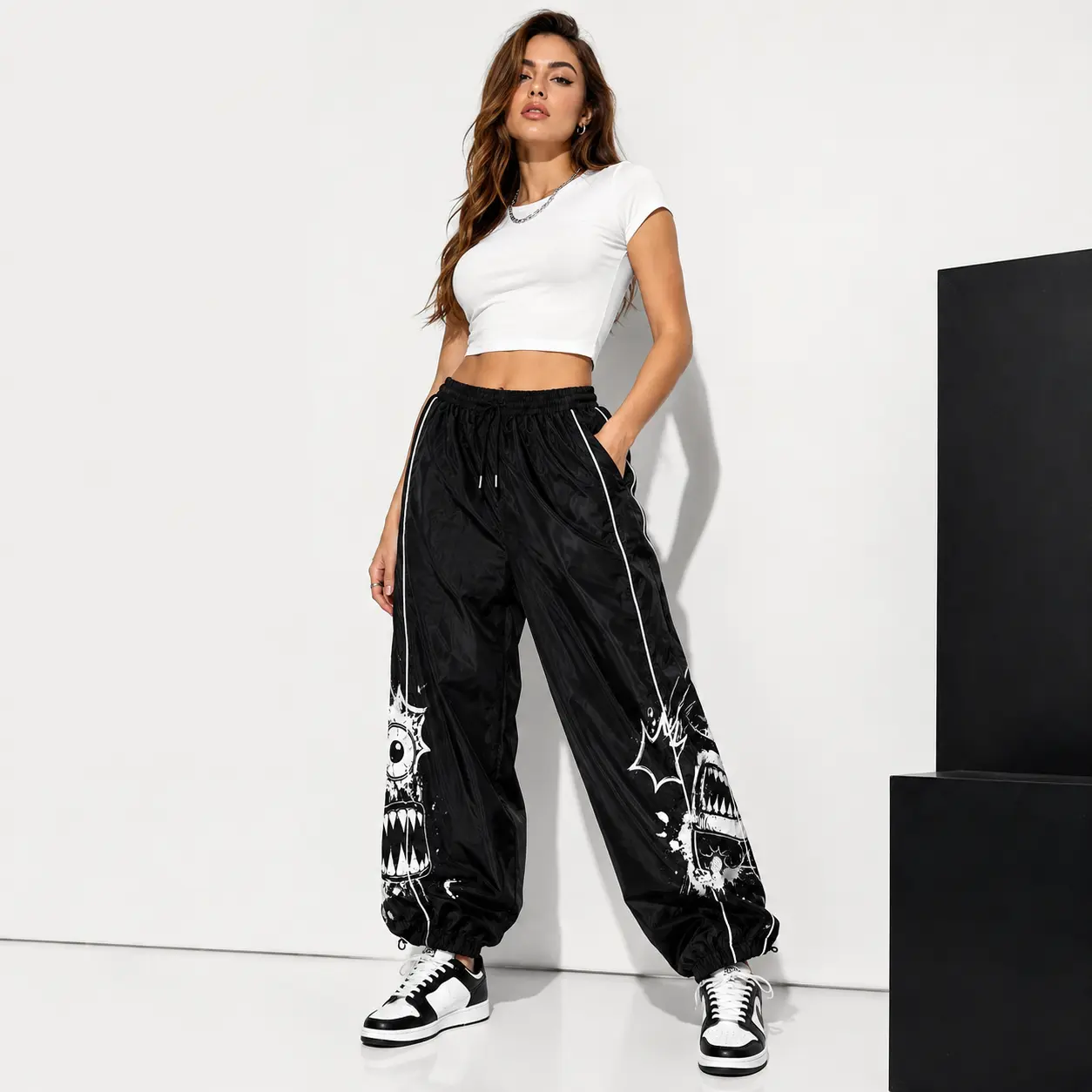 Women’s Black Graphic Jogger Pants, Loose Fit Streetwear Track Pants with Monster Eyeball Print, White Contrast Piping, Adjustable Drawstring Waist and Gathered Ankle Cuffs, Y2K Baggy Pants for Casual Outfits and Travel