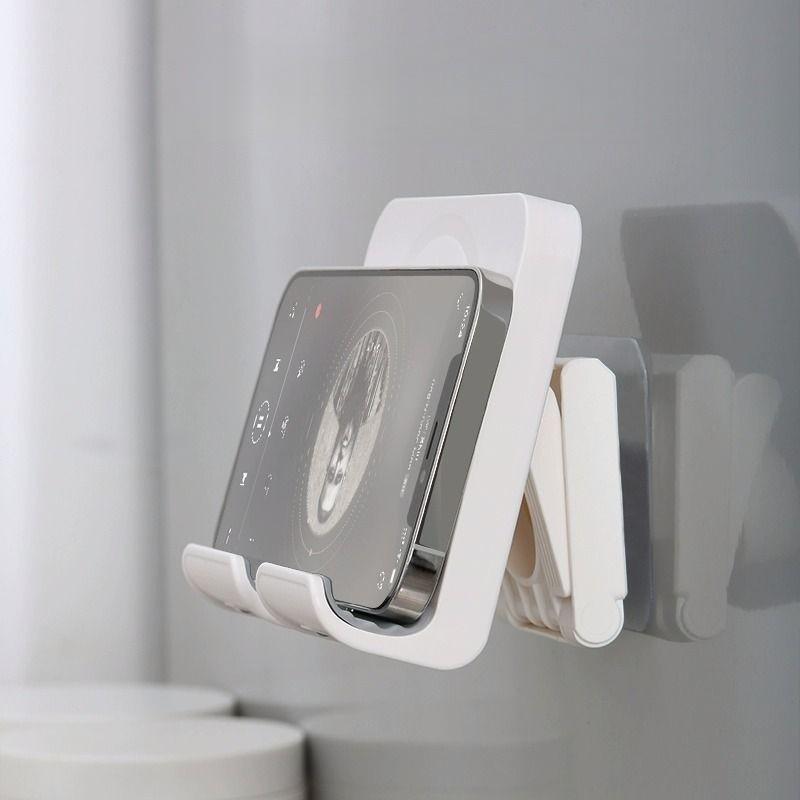 A wall-mounted phone holder, Electronic Mobile Accessory, Cell Phone Holders, featuring punch-free installation and adjustable angle, is a practical gift suitable for installation on walls in bedrooms, living rooms, kitchens, bathrooms, etc