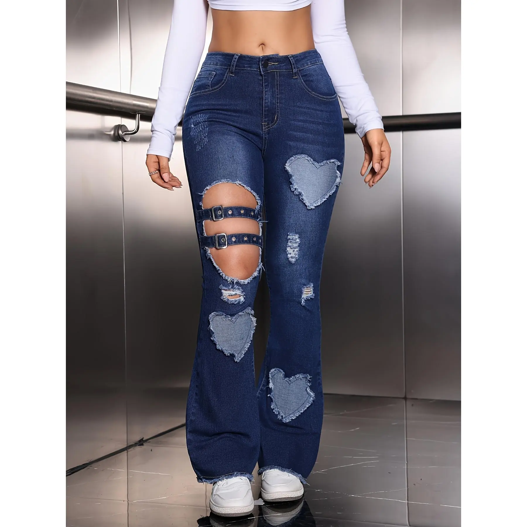 A pair of mid-high waist elastic denim flared pants with heart-shaped embroidered patches, washed distressed holes, hollowed-out details, attached straps and D-ring buckles, and frayed hem design
