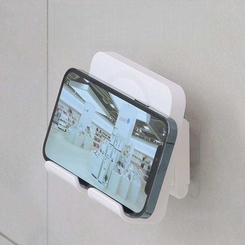 A wall-mounted phone holder, Electronic Mobile Accessory, Cell Phone Holders, featuring punch-free installation and adjustable angle, is a practical gift suitable for installation on walls in bedrooms, living rooms, kitchens, bathrooms, etc