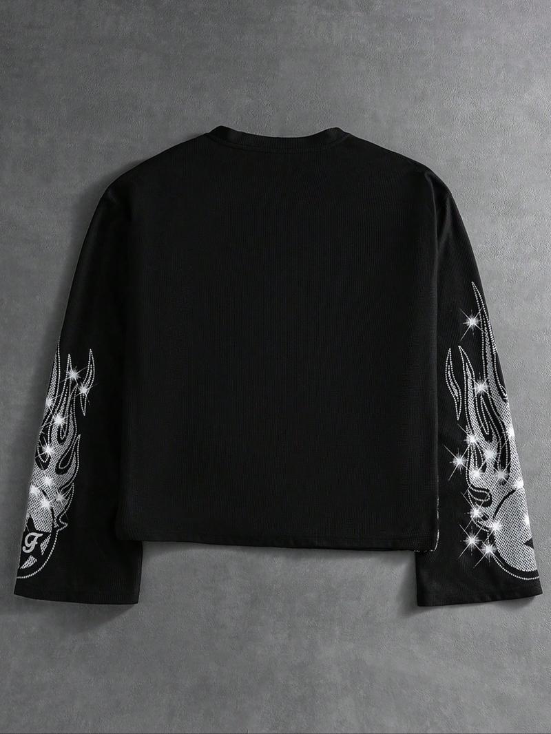 This men's two-piece set features a gothic streetwear design, including a long-sleeved T-shirt with a shimmering flame print and black flared trousers adorned with rhinestones and lettering.