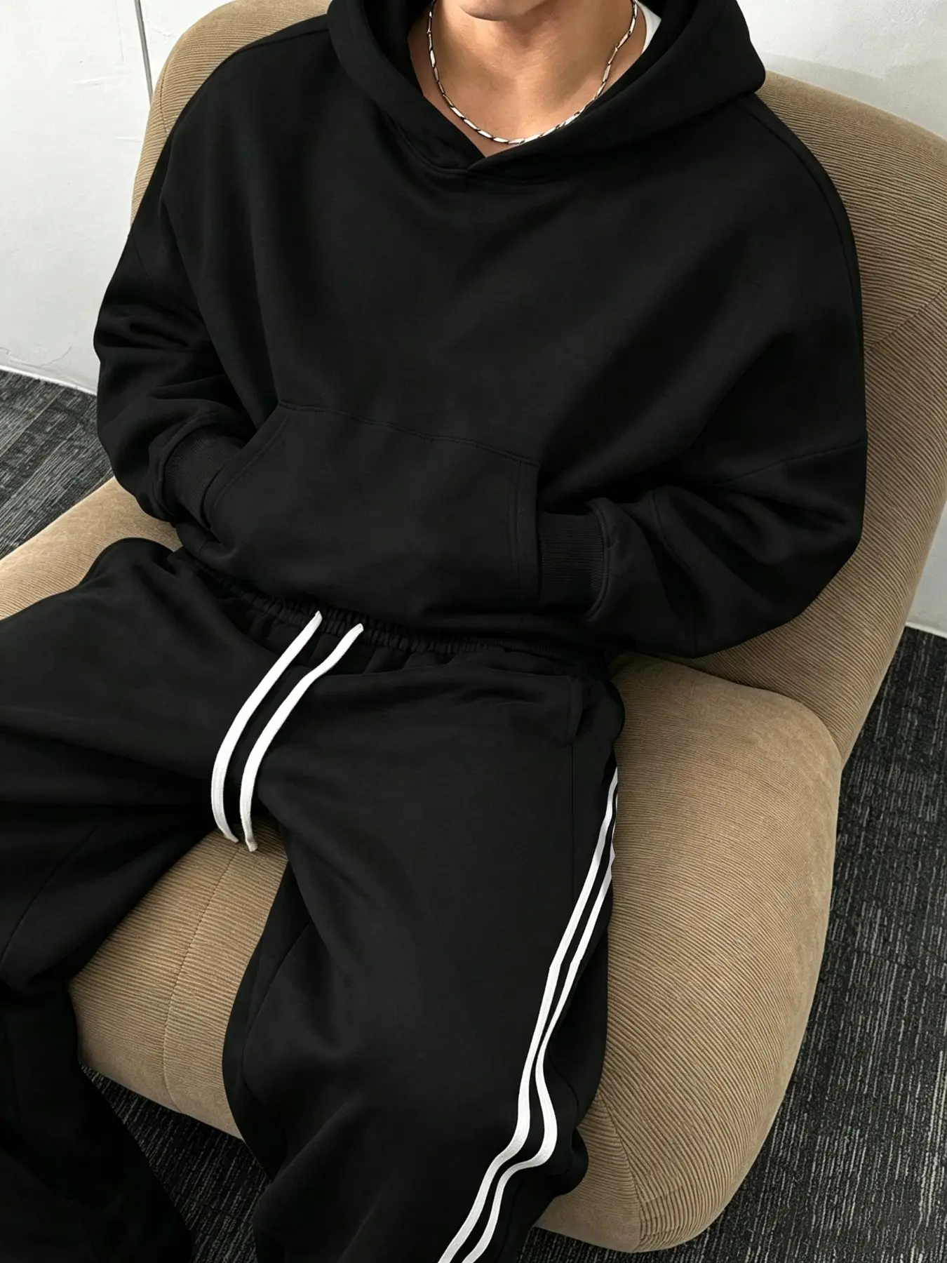 A fleece-lined matching sweatshirt and jogger set designed for warmth during autumn and winter. It features a hooded sweatshirt paired with curved-seam joggers, offering a stylish look in a classic, solid-color design.