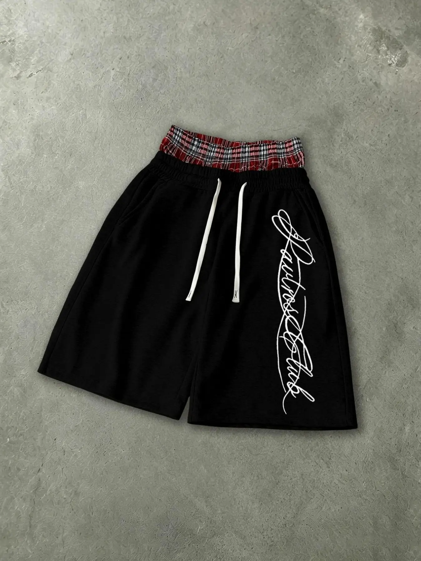 Black sweat shorts with double-layer waistband, plaid spliced waist trim, cursive letter print on side, drawstring. Loose five-length cut, vintage American street style for summer.