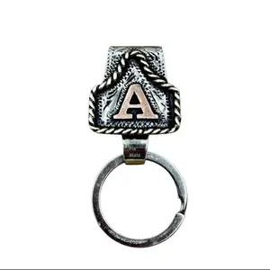 Trendy Chic Deco handmade belt-loop keychain featuring an ear-tag shape and a brass initial charm. Custom-made. Origin: Texas. Fashion accessory. Father's Day gift.