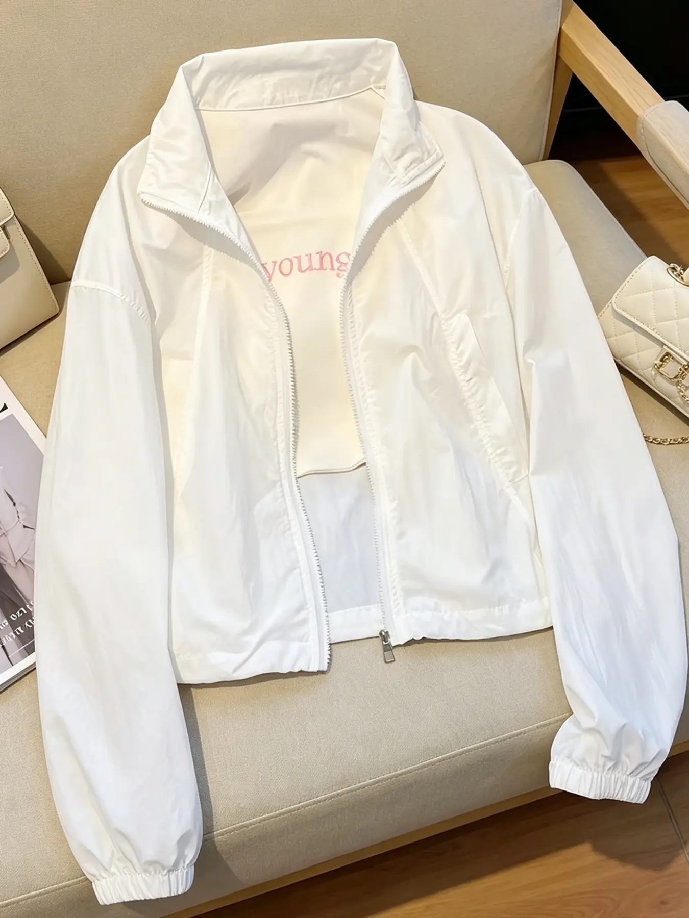 A women's fashionable pure white stand up collar zipper jacket, with lightweight and slightly wrinkled sleeves and side pockets, suitable for commuting, outdoor play, indoor and outdoor wear