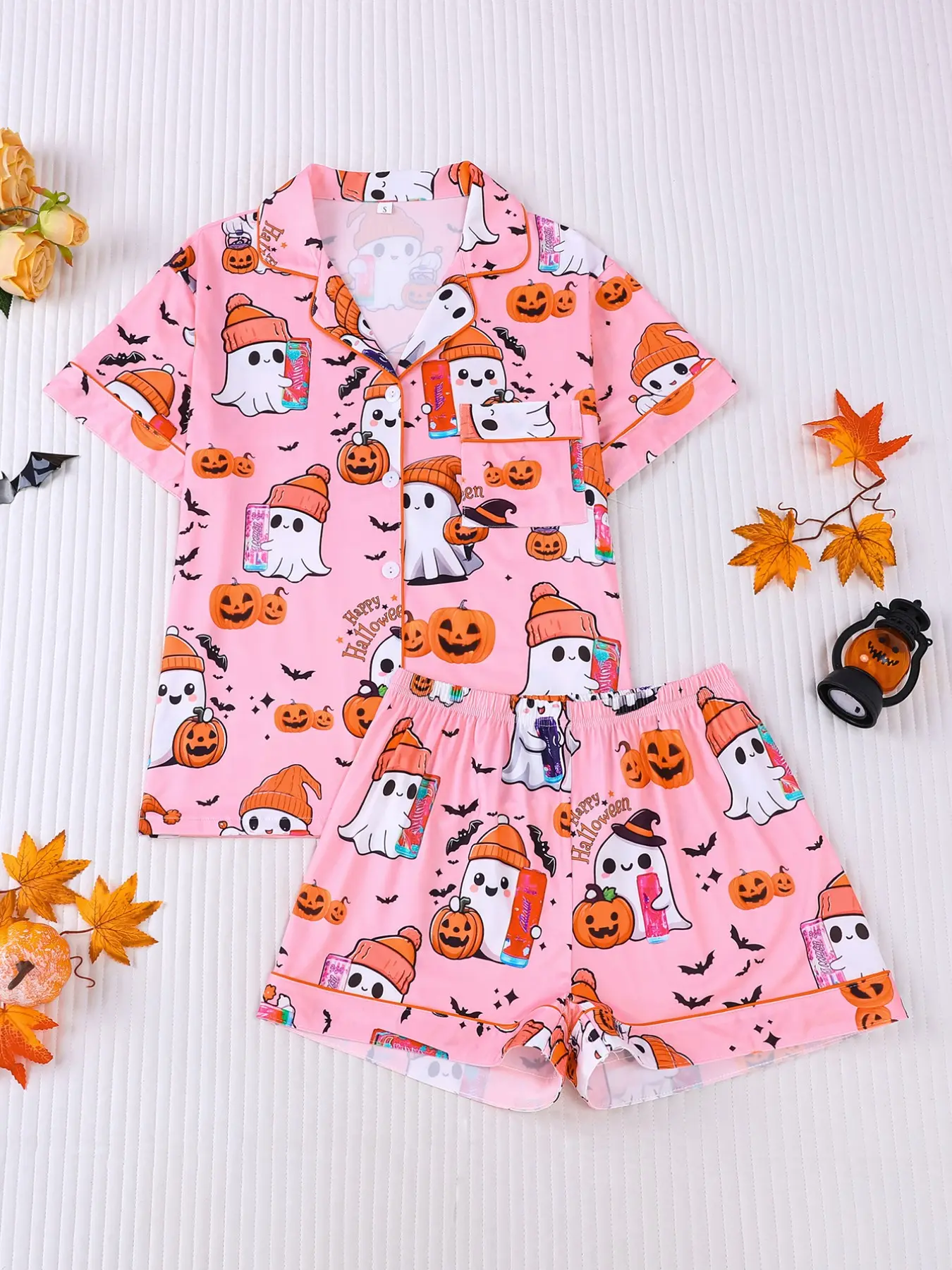 Women's 2-piece Halloween pajama set, pink base with cute ghosts in beanies, pumpkins and bats prints. Sweet playful style with orange contrast trim. Lapel short sleeve top with pocket, elastic waist shorts, soft comfy loungewear for all-season wear