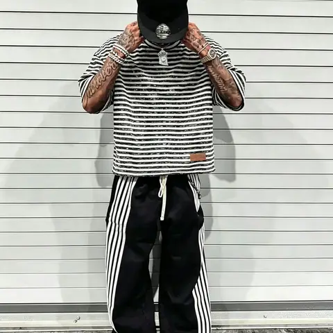 A cropped T-shirt featuring a, dropped-shoulder fit and a clean, bold black-and-white striped pattern. Crafted from cotton with a distressed texture, it incorporates leather-material detailing—an essential Aesthetic staple for everyday streetwear.