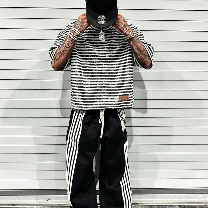 A cropped T-shirt featuring a, dropped-shoulder fit and a clean, bold black-and-white striped pattern. Crafted from cotton with a distressed texture, it incorporates leather-material detailing—an essential Aesthetic staple for everyday streetwear.