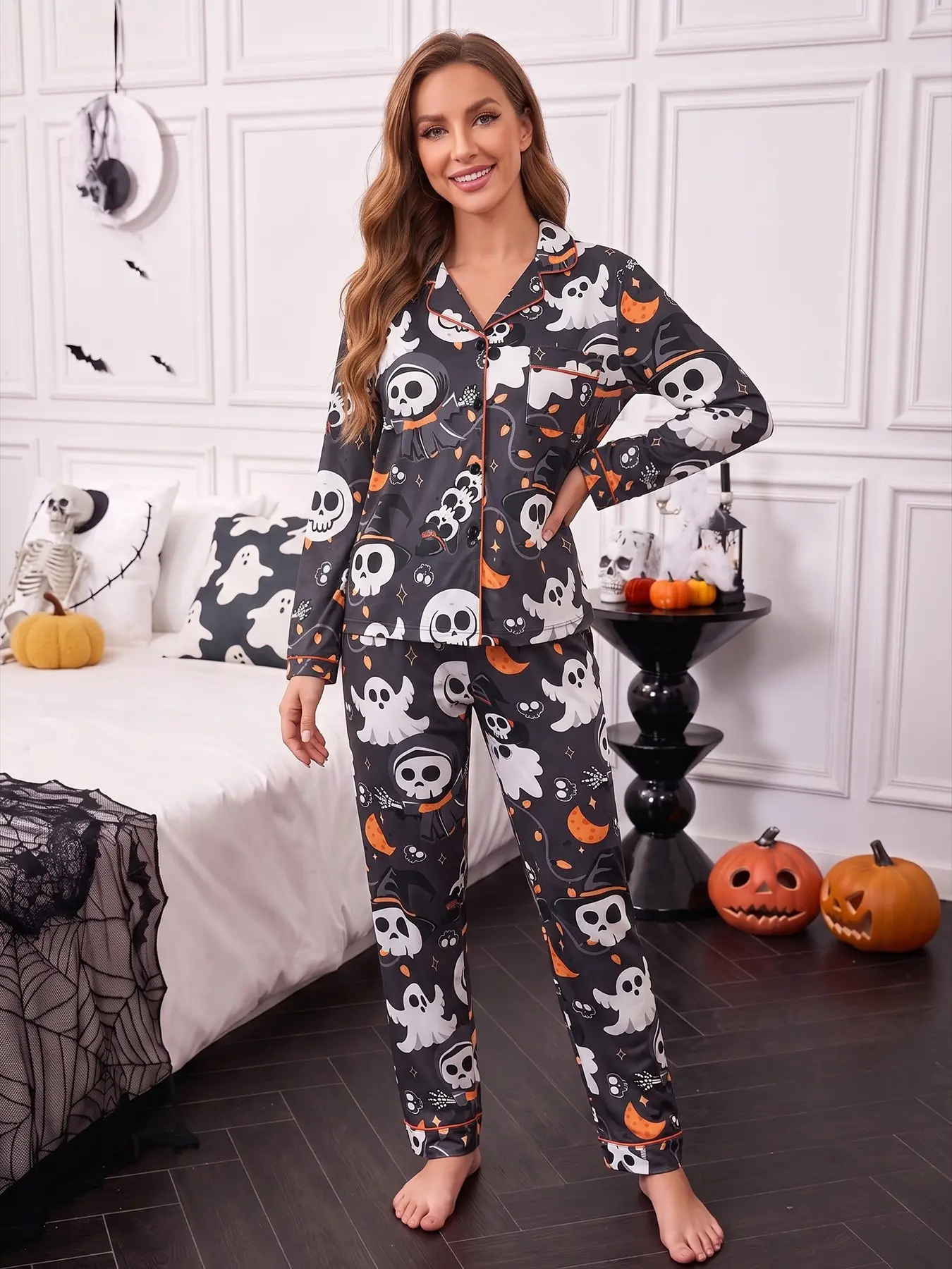 Women's 2-piece pajama set, black base printed with Halloween skeletons, grim reaper, ghosts, moons, stars & skeleton hands, cool Halloween style. Orange piping lapel top with pocket, soft elastic long pants, all-season casual women loungewear
