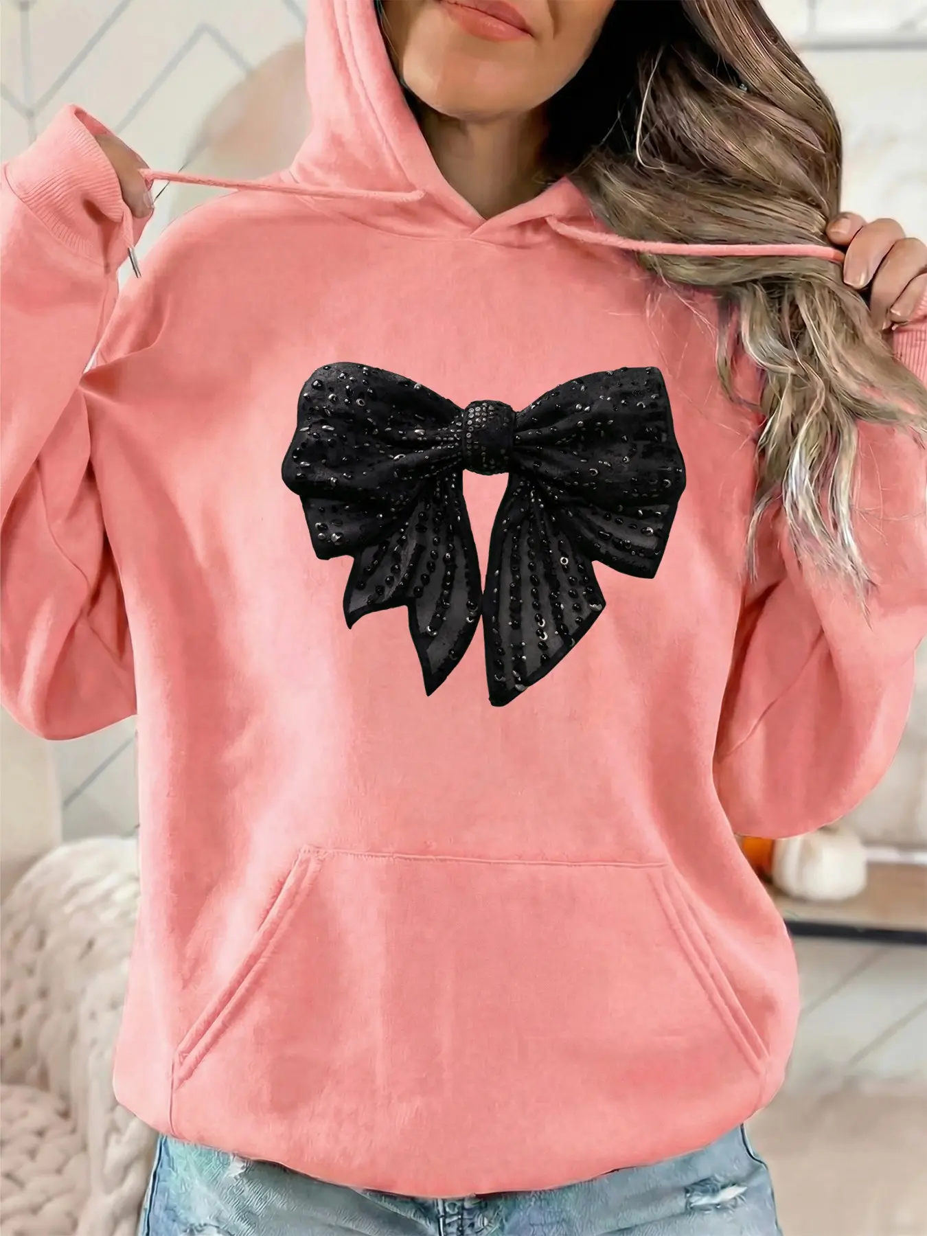 The women's fashionable hooded sweatshirt features a black bow pattern print. It has drawstring kangaroo pockets. It is a fall/winter casual sportswear sweatshirt suitable for casual parties and sports activities.