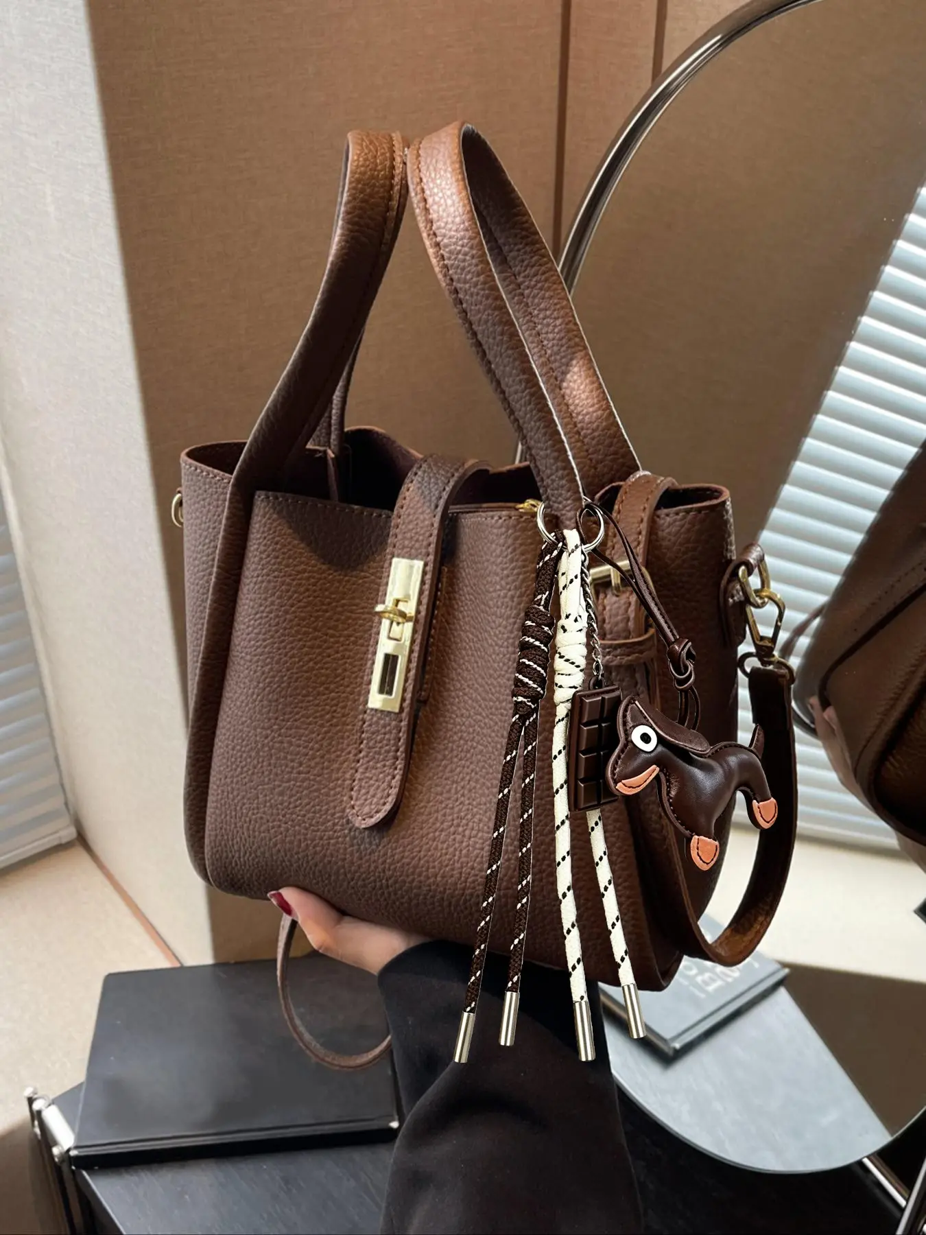 A niche fashion minimalist clasp design crossbody bag, paired with a dachshund tassel charm, featuring a detachable long shoulder strap. A gentle, casual, everyday bag that's perfect for commuting, shopping, and traveling.