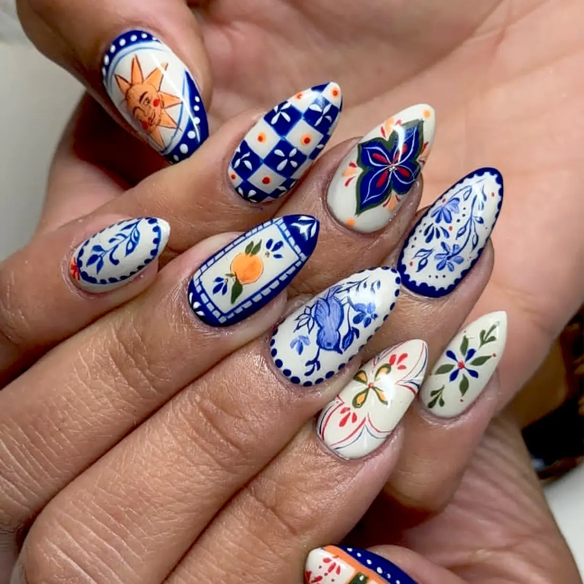24pcs short almond shaped blue nails featuring a Mediterranean ceramic-style design with blue-and-white floral, bird, sun, and orange tile prints. These vintage Mexican-style fake nails Press On Nail are perfect for a variety of occasions