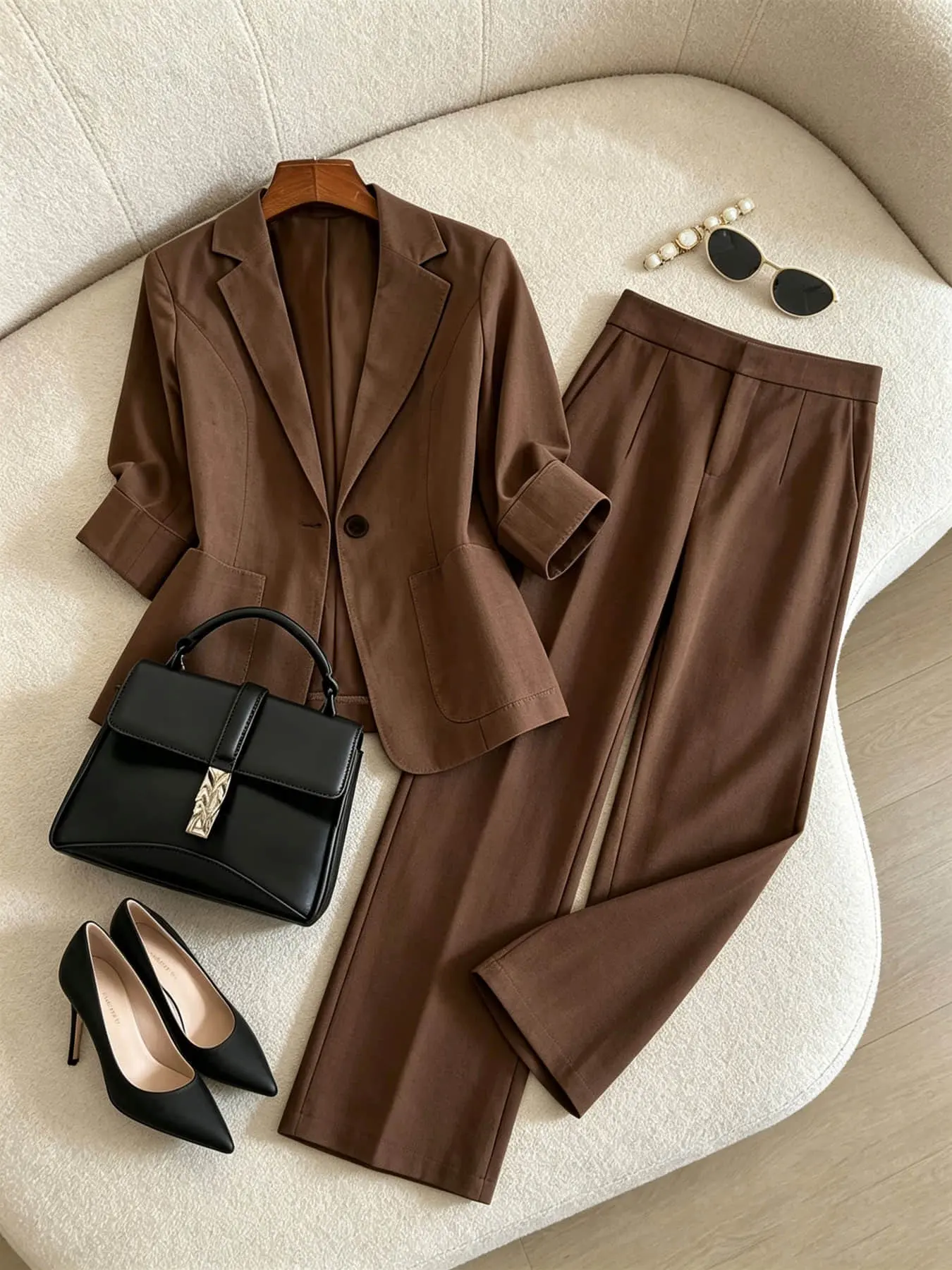 Two-piece women's fashion set in brown, Minimalist featuring a lapel, single row of buttons, curved pockets, a mid-length sleeve blazer, and high-waisted wide-leg pants. Suitable for all seasons and ideal for both business occasions and casual street wear