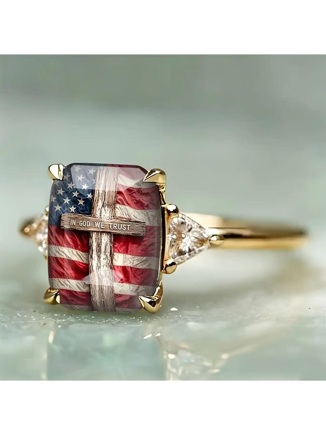 A silver four-claw rectangular American flag cross-patterned ring. The ring face is printed with a vintage Stars and Stripes flag and a wood-grain cross, with the inscription "IN GOD WE TRUST" engraved on it.