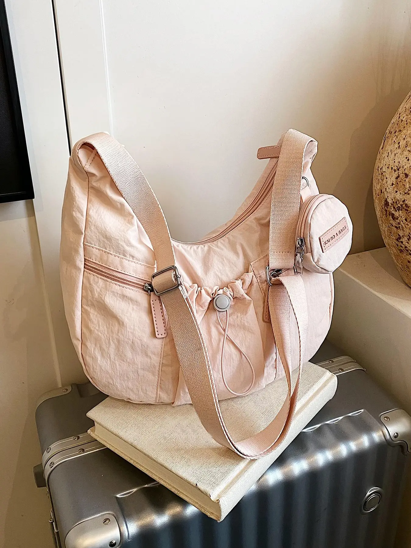 Casual and relaxing versatile drawstring pocket shoulder bag, large capacity simple and stylish personalized crossbody bag, multi pocket compartment design, with the same small bag pendant, suitable for commuting and shopping