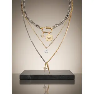 Women's gold stackable necklaces, available in various thicknesses, featuring a cross, carabiner, and a protective eye pendant. A stylish bohemian vintage-inspired jewelry set, perfect for gifting.