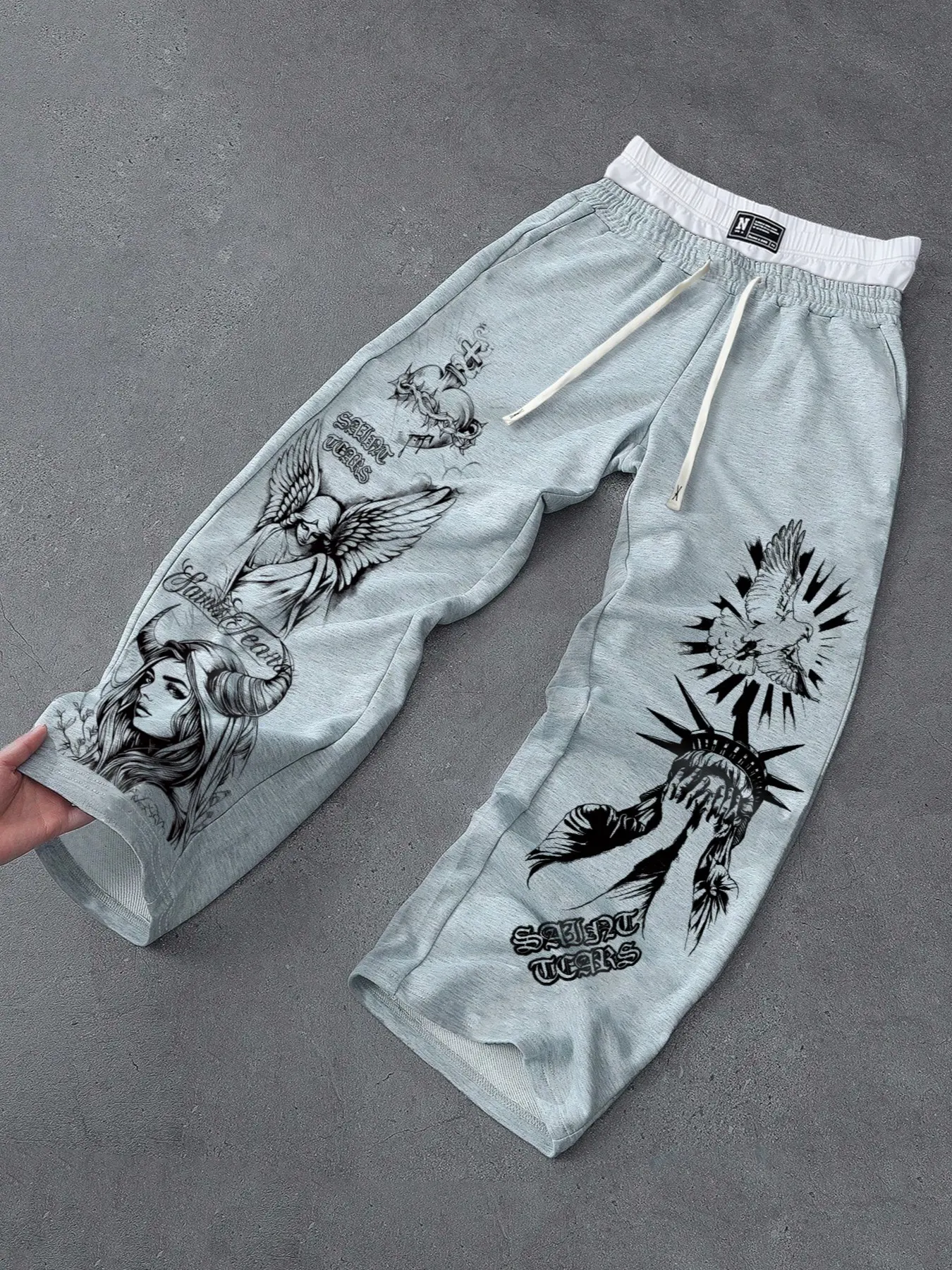 Men's Chicano retro tattoo print athletic shorts, heather gray wide-leg cuffed cropped pants, drawstring waist with contrasting white trim, dark graphic prints featuring angels, devils, women, the Statue of Liberty and doves, breathable baggy streetwear t