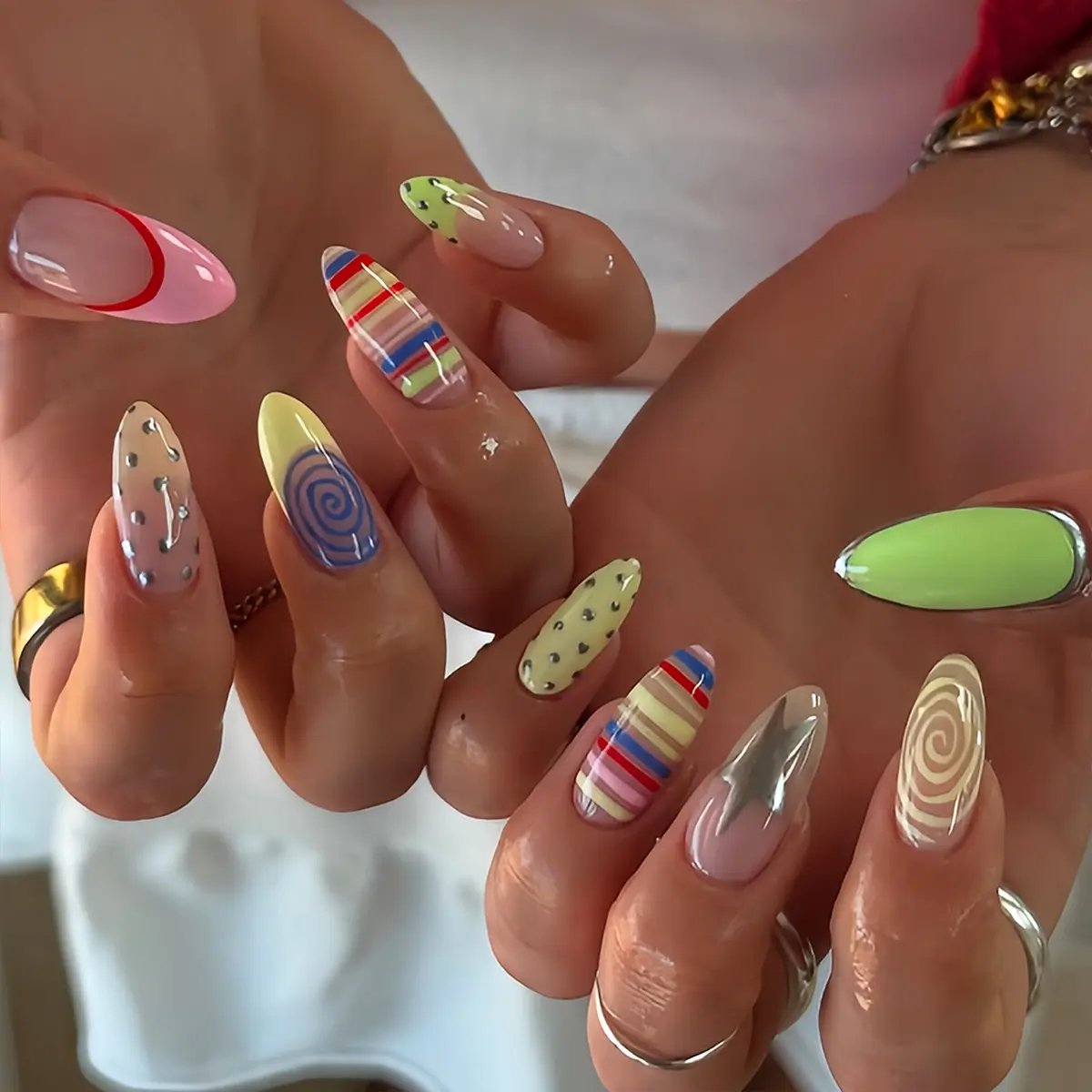 Set of 24 almond-shaped Y2K press-on nails, Artificial nails, featuring a summer-ready blue and yellow color-block spiral stripe design, accented with soft green, gold leaf, stars, and polka dots, perfect for young women