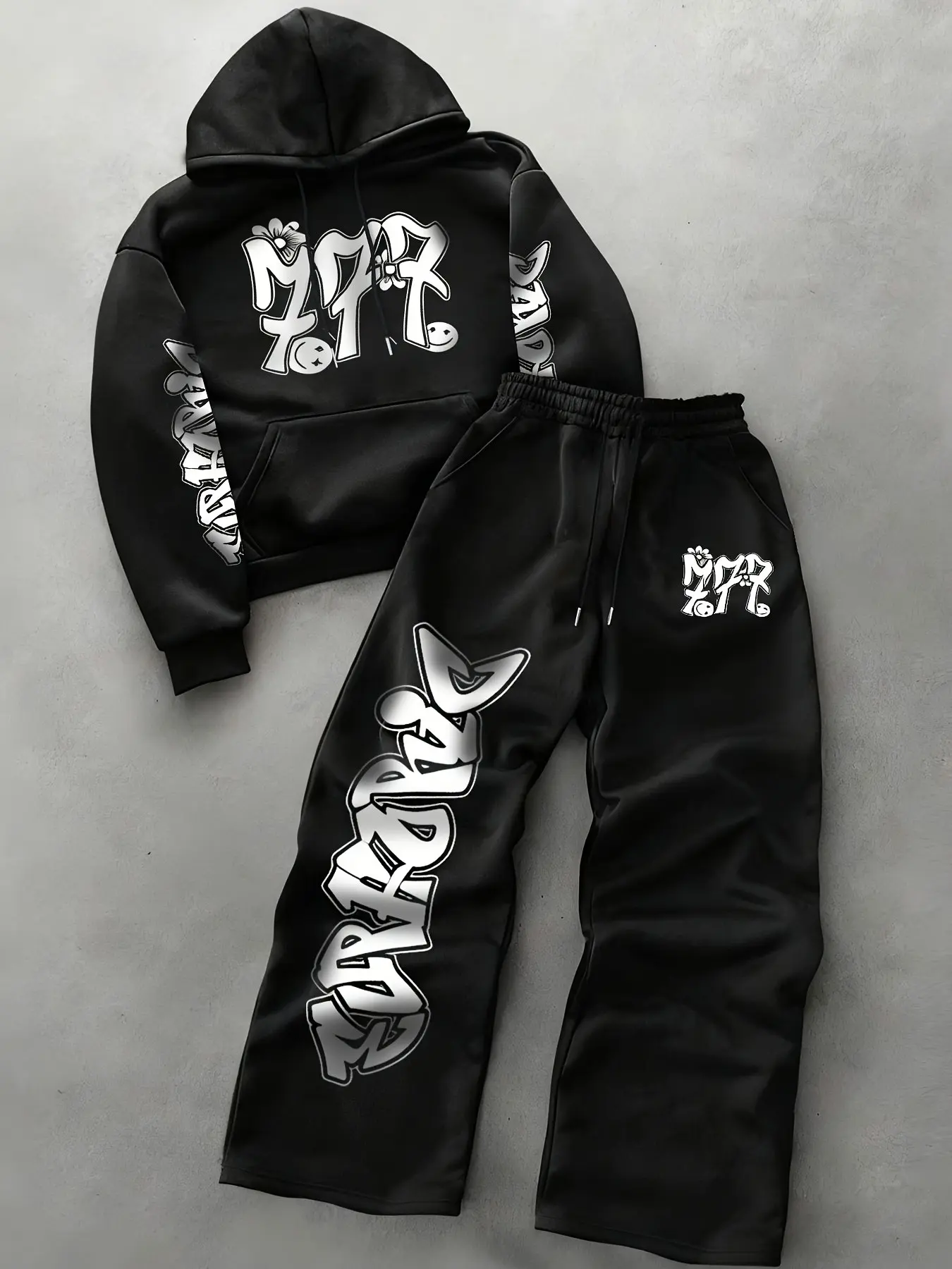 White Graffiti Two-Piece Tracksuit: Oversized Printed Hoodie and Wide-Leg Sweatpants. Crafted from soft fabric with black letter prints, it features a drawstring hood, elastic waistband and pockets. Ideal for street-style looks for school, skateboarding,