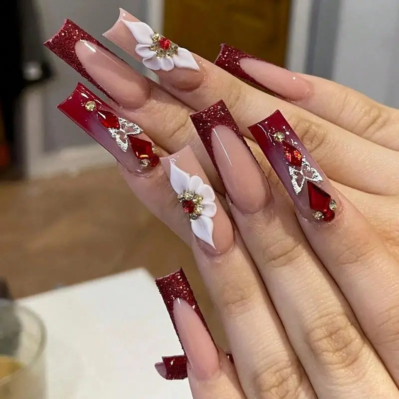 Rectangular burgundy press-on nail set, red glitter V-shape French tips, ruby bow rhinestone, 3D white flowers with red gemstone centers reusable fake nails suitable for weddings, anniversary banquets, and anniversary nail art press-on nails