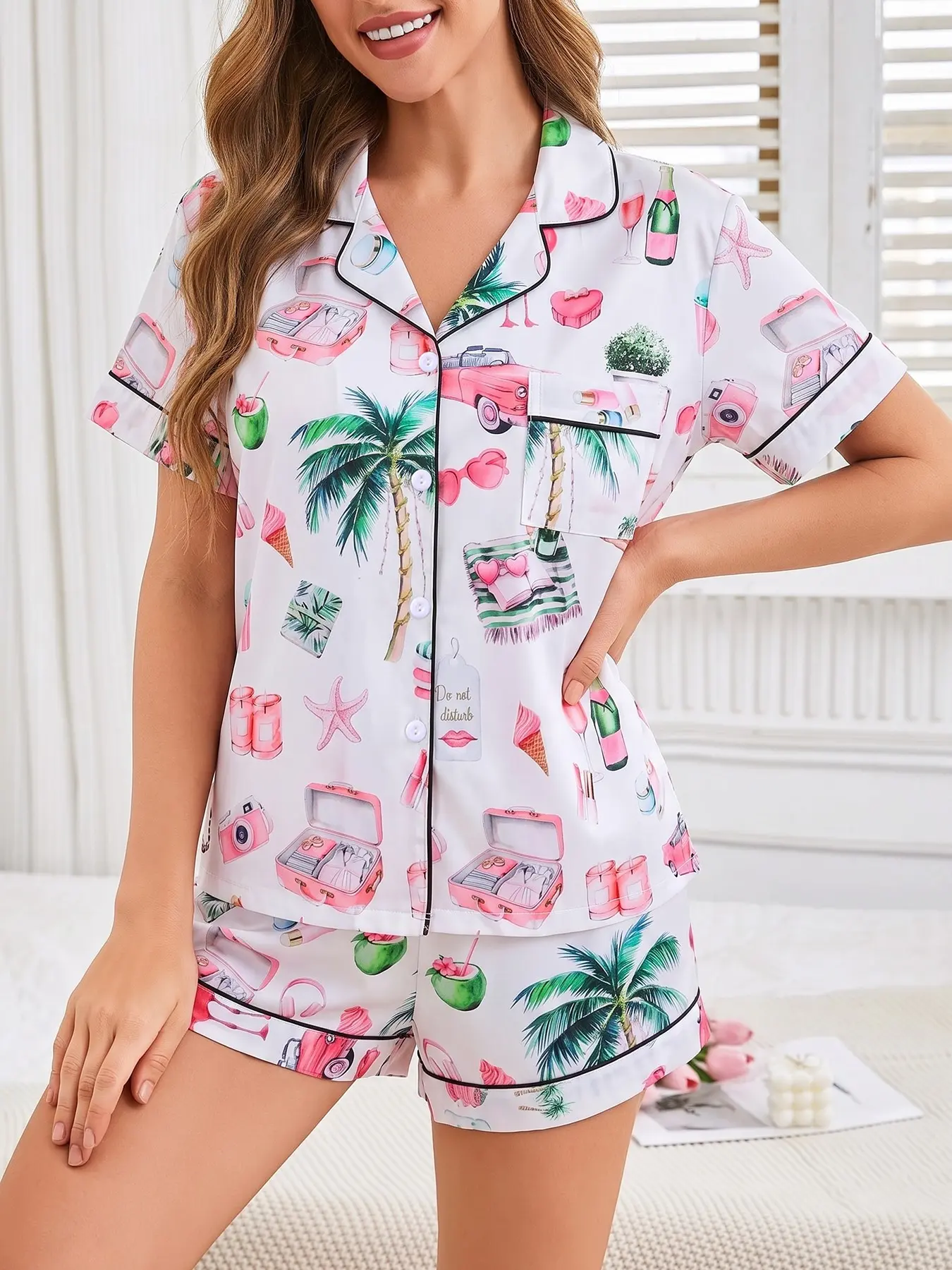 Women's 2-piece pajama set with pink tropical island vacation print of palm trees, flamingos & suitcases on white base, black contrast piping. Lapel short sleeve top with pocket, soft elastic waist shorts, casual women loungewear for all seasons