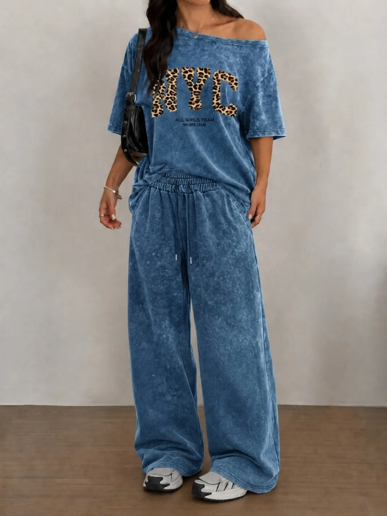 A leopard-print set in washed cotton featuring an off-the-shoulder, wide-neck design that highlights the collarbones and a bold 'NYC' leopard print, the loose-fitting T-shirt pairs with wide-leg drawstring trousers to flatter the silhouette, Clothes