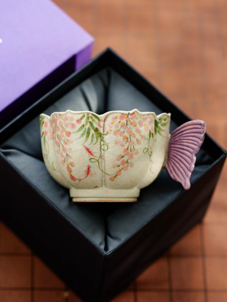 The hand-painted wisteria and carp pattern coffee cup, crafted by artisans, is an attractive and practical ceramic tea cup with a vintage style and vibrant colors