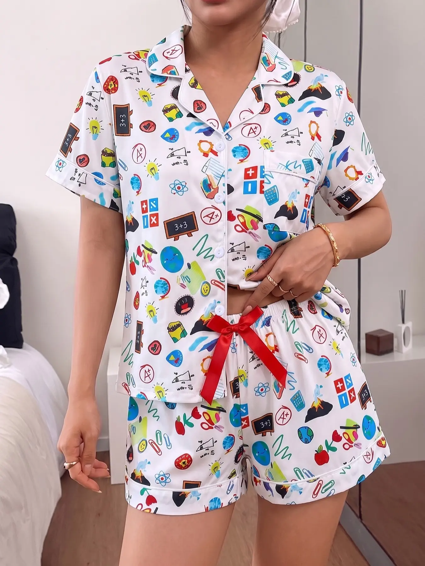 Women's 2-piece pajama set with white cartoon school prints, blackboards, graduation caps & stationery, lively college style. White piping lapel top with pocket, elastic shorts with red bow, soft all-season casual loungewear for women