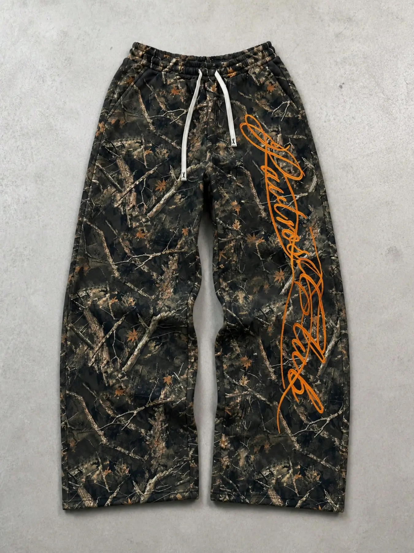 Camouflage print wide-leg sweatpants, orange handwritten-style loose streetwear pants, with an elastic drawstring waist and soft, comfortable fabric. Perfect for street photography, skateboarding, music festivals, and weekend casual outings.