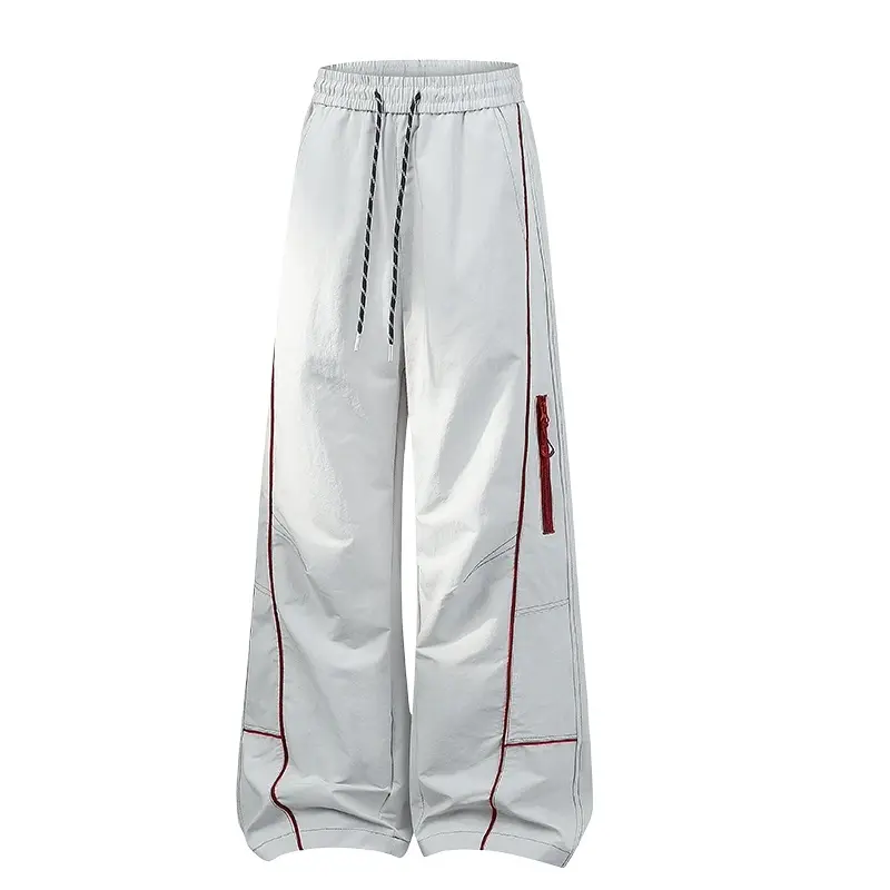 Elastic drawstring waist wide leg casual trousers, red contrast piping stitching, side zipper pockets, segmented panel cutting design, lightweight crinkled fabric, loose baggy wide silhouette, streetwear long pants for daily outdoor outfits