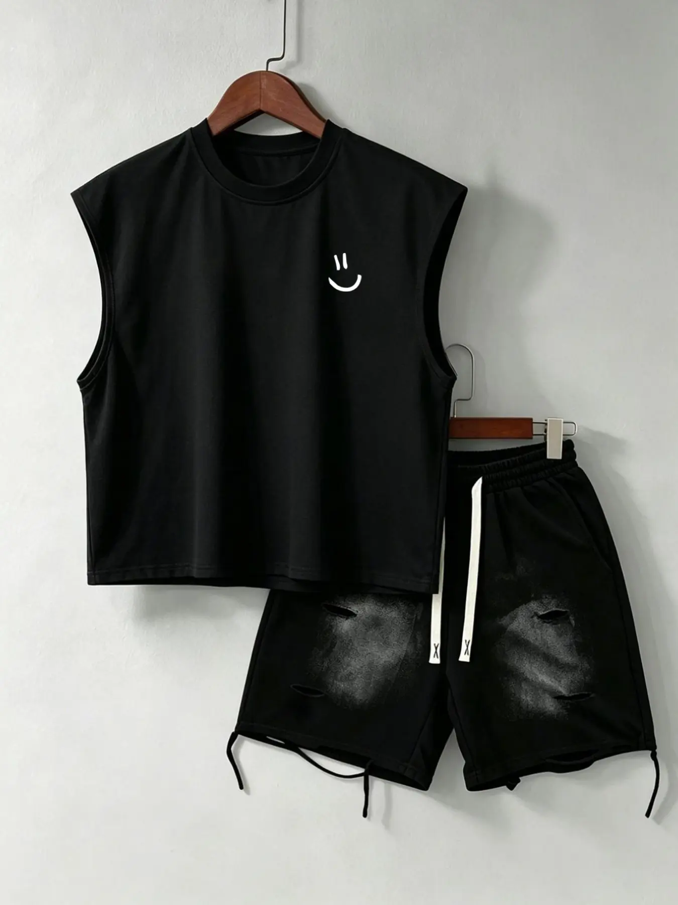The American-style sleeveless two-piece set includes a high-street casual style cropped vest with a graphic smiley face print and a gradient distressed drawstring shorts.