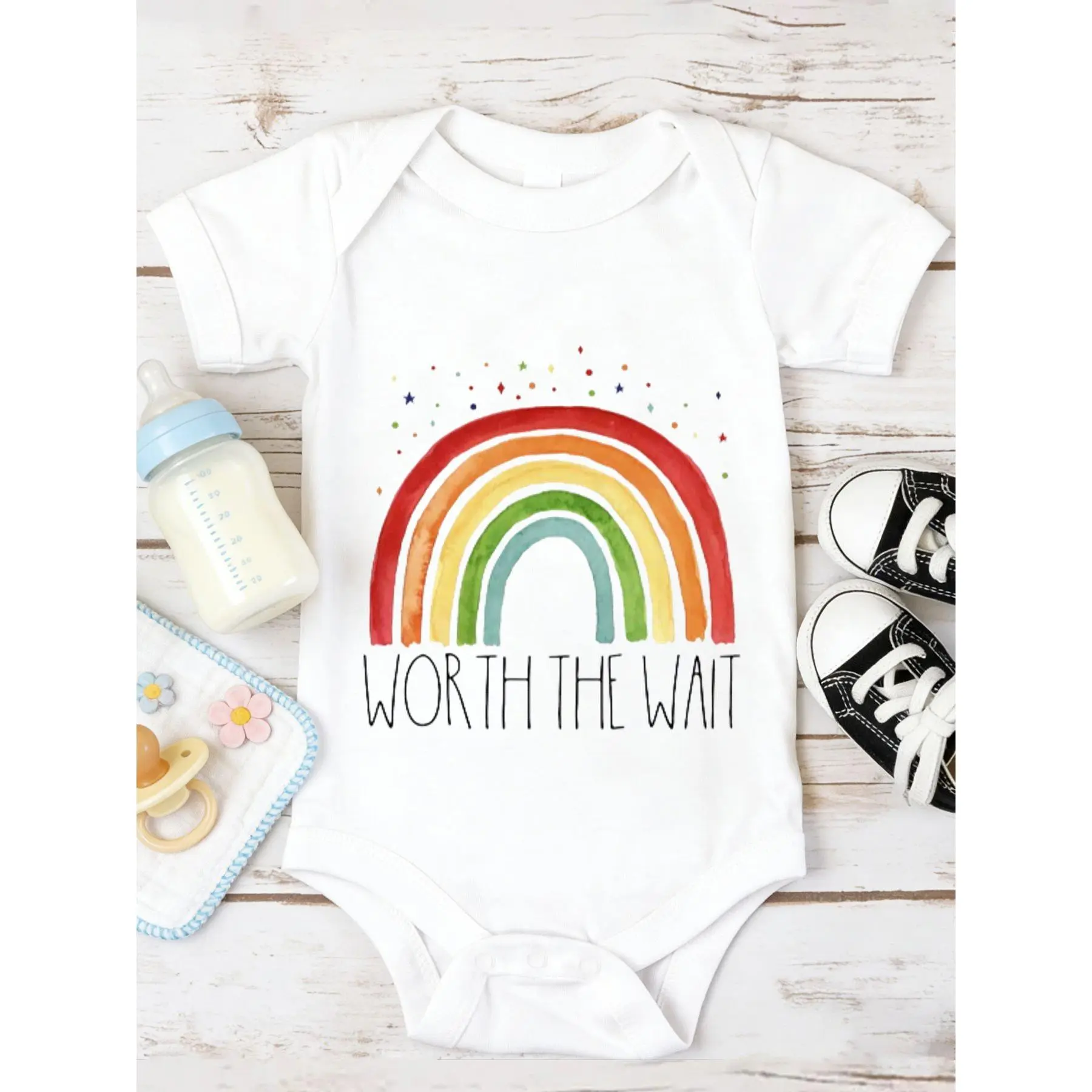 100% Cotton Baby Onesie, Rainbow Watercolor Style with Red Orange Yellow Green Blue Segments, Multicolored Dots Stars, 'WORTH THE WAIT' Handwritten Bold Black Text, Matching White Baby Bottle Blue Cap, Light Blue White Pacifier Clip with Pacifier