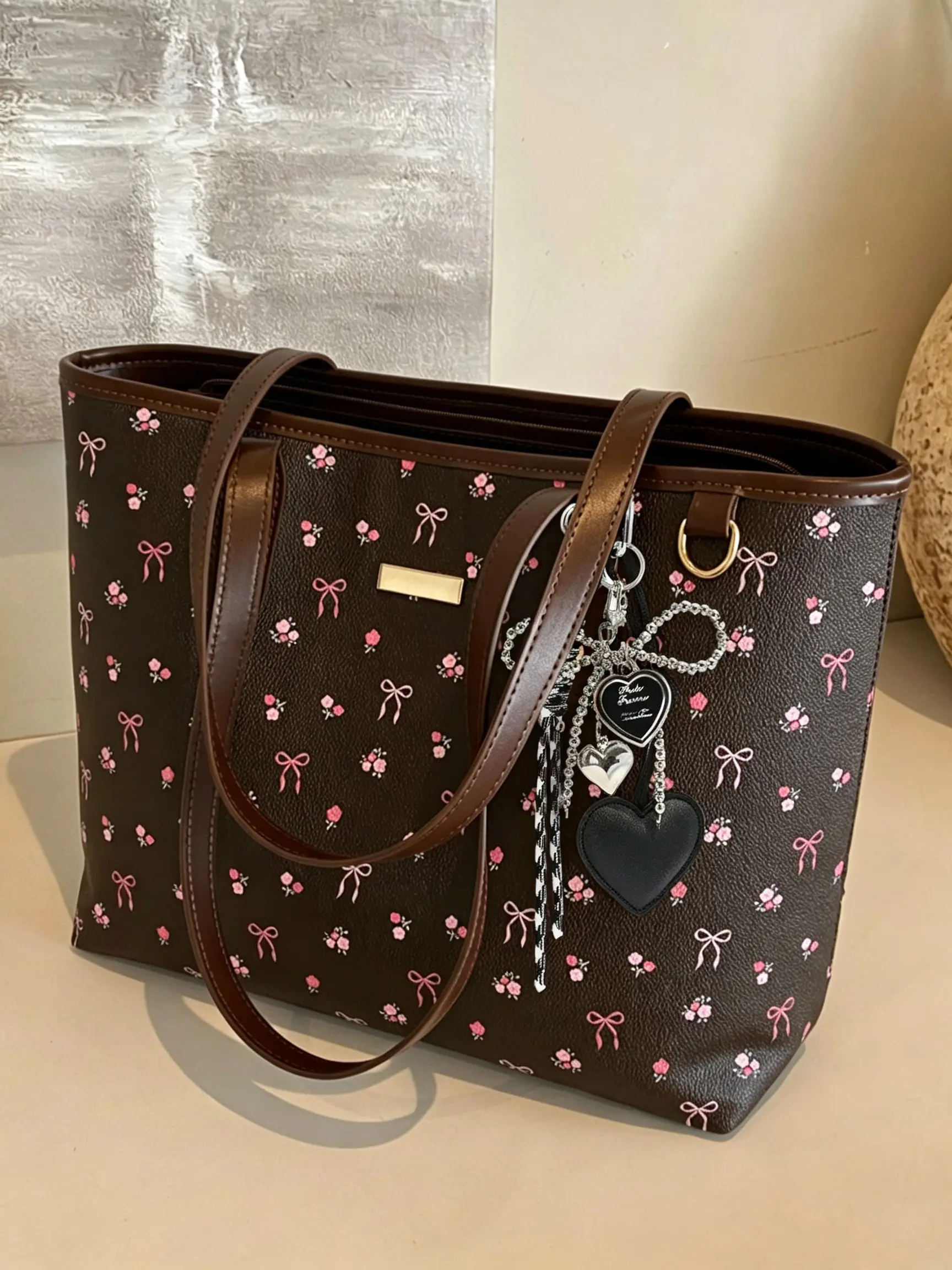 Korean-style gentle floral print PU Leather tote bag, featuring a bow and heart charm on the body, large open-top design, a lightweight and versatile shoulder bag perfect for students for classes, commuting, or outings.