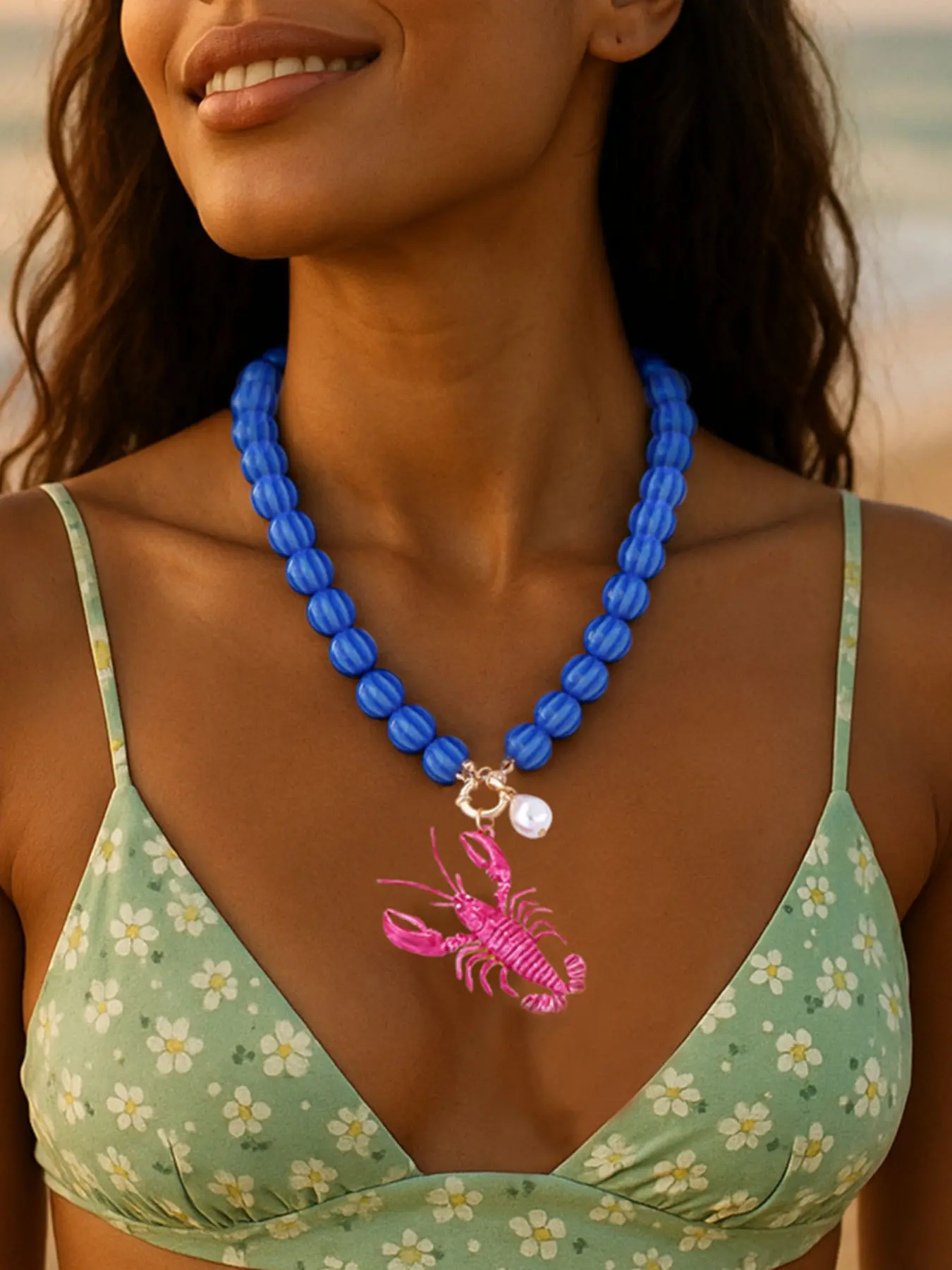 Versatile beaded necklace featuring an alloy and enamel lobster pendant perfect for a beachy, resort-style look.