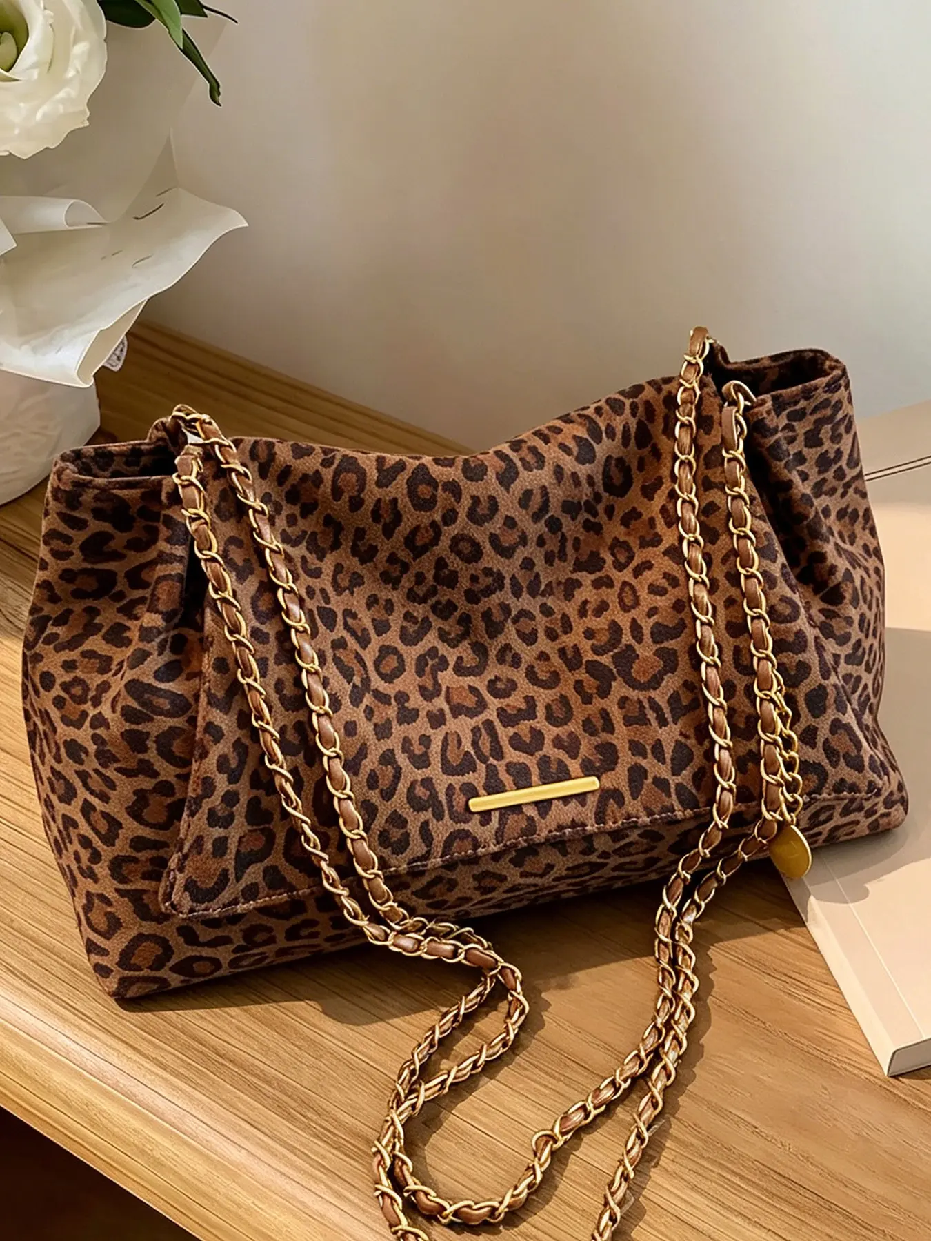 A casual fall-winter stylish leopard print crossbody bag with a minimalist vibe, made of delicate suede material, featuring a thin gold chain shoulder strap, perfect for everyday wear, commuting, shopping, and outings with a trendy touch.
