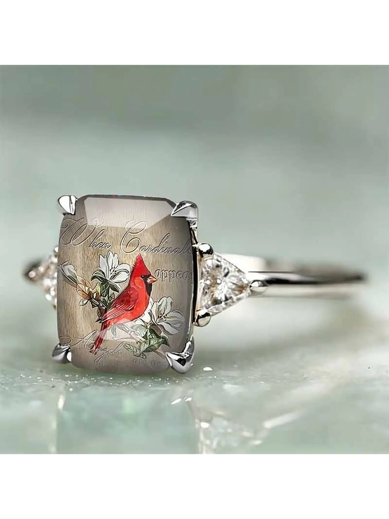 Silver four-claw rectangular red cardinal bird print ring, with a light wood grain texture as the base color, featuring North American cardinal birds, white flowers and vintage English text. The sides are complemented by triangular imitation diamonds.
